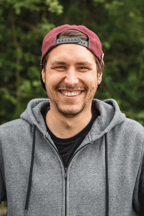 Porträt von Carl Victor Martin-Maus mit Basecap vor grünen Bäumen