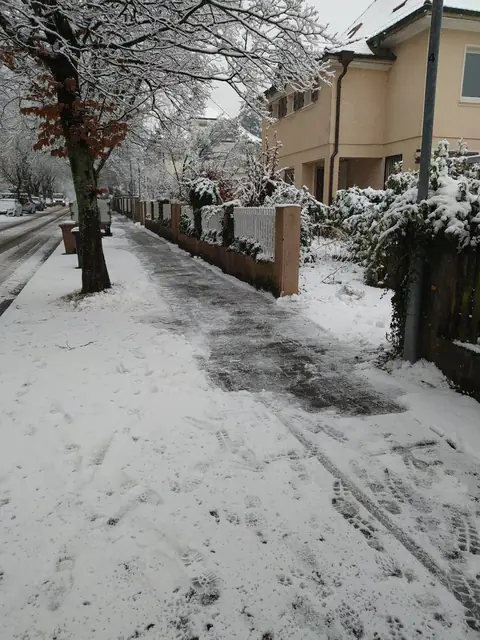 Geräumter und gestreuter Gehweg an einer verschneiten Wohnstraße